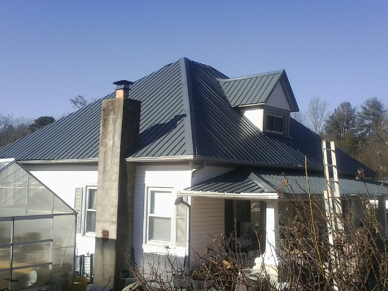Dark blue standing seam metal roof on a white farmhouse with dormer — Slate & Tile Roof Repair by Roofing Brothers in Momence