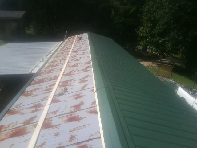 Old rusted panels beside newly installed green metal roofing — Wind Damage Roof Repair by Roofing Brothers in Momence