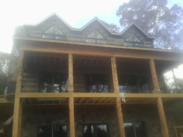 Dormers and porch framing on a large log home under construction — Roof Coating work by our crew in Momence