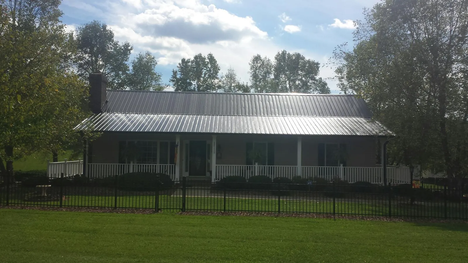Gray metal roof on a brick ranch with a full width front porch — Gutter Guard Installation work by our crew in Momence