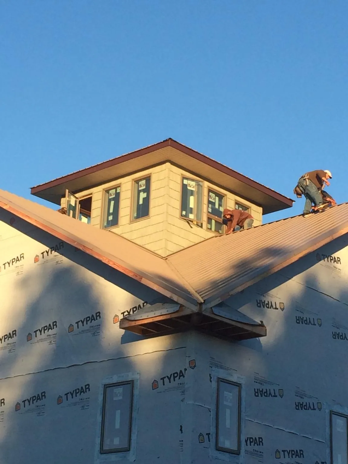 Roofers working around a rooftop cupola on a new metal roof at sunset — Roof Waterproofing in Momence by Roofing Brothers